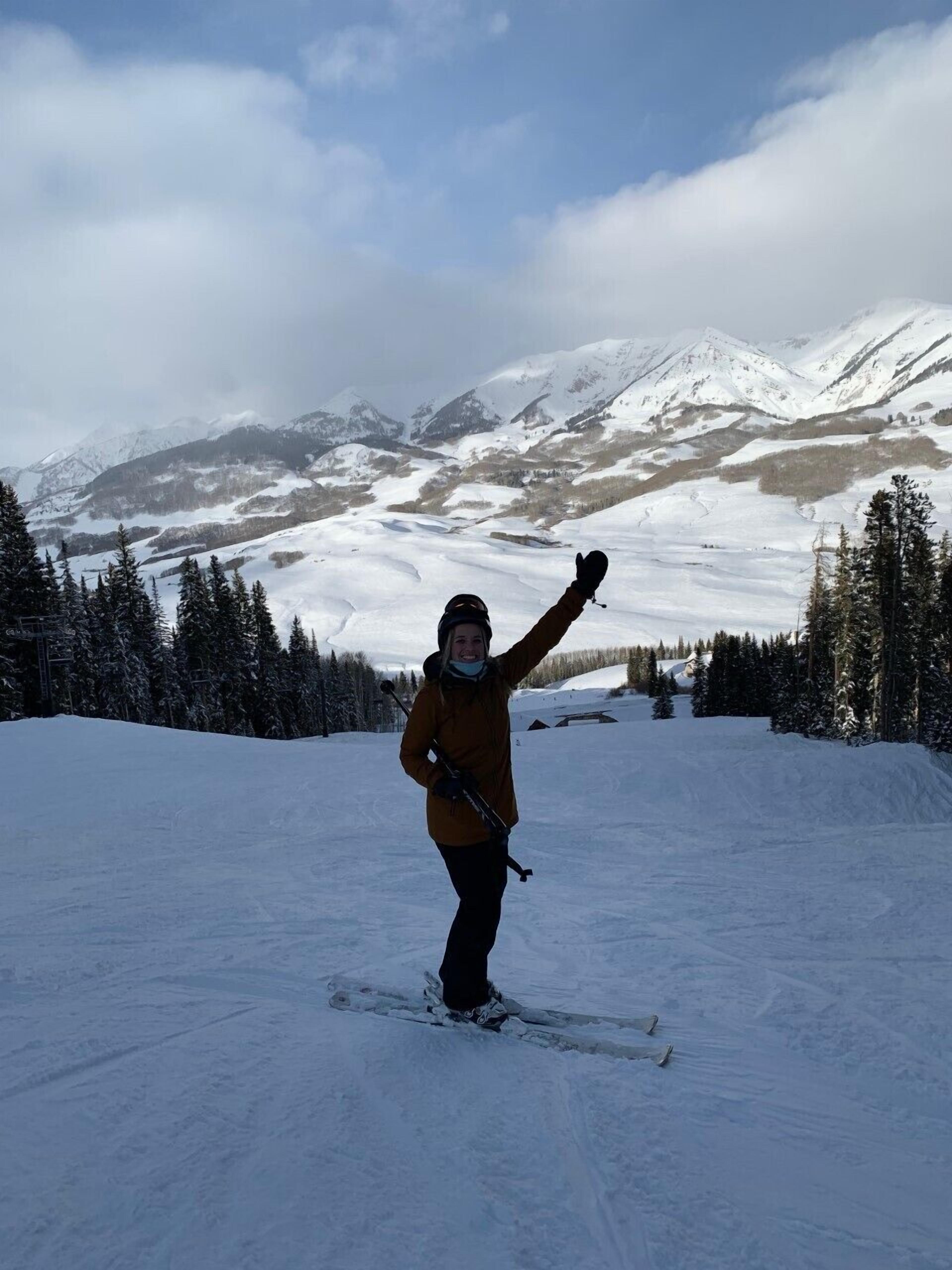 A person skiing on a snowy slope with mountains in the background.