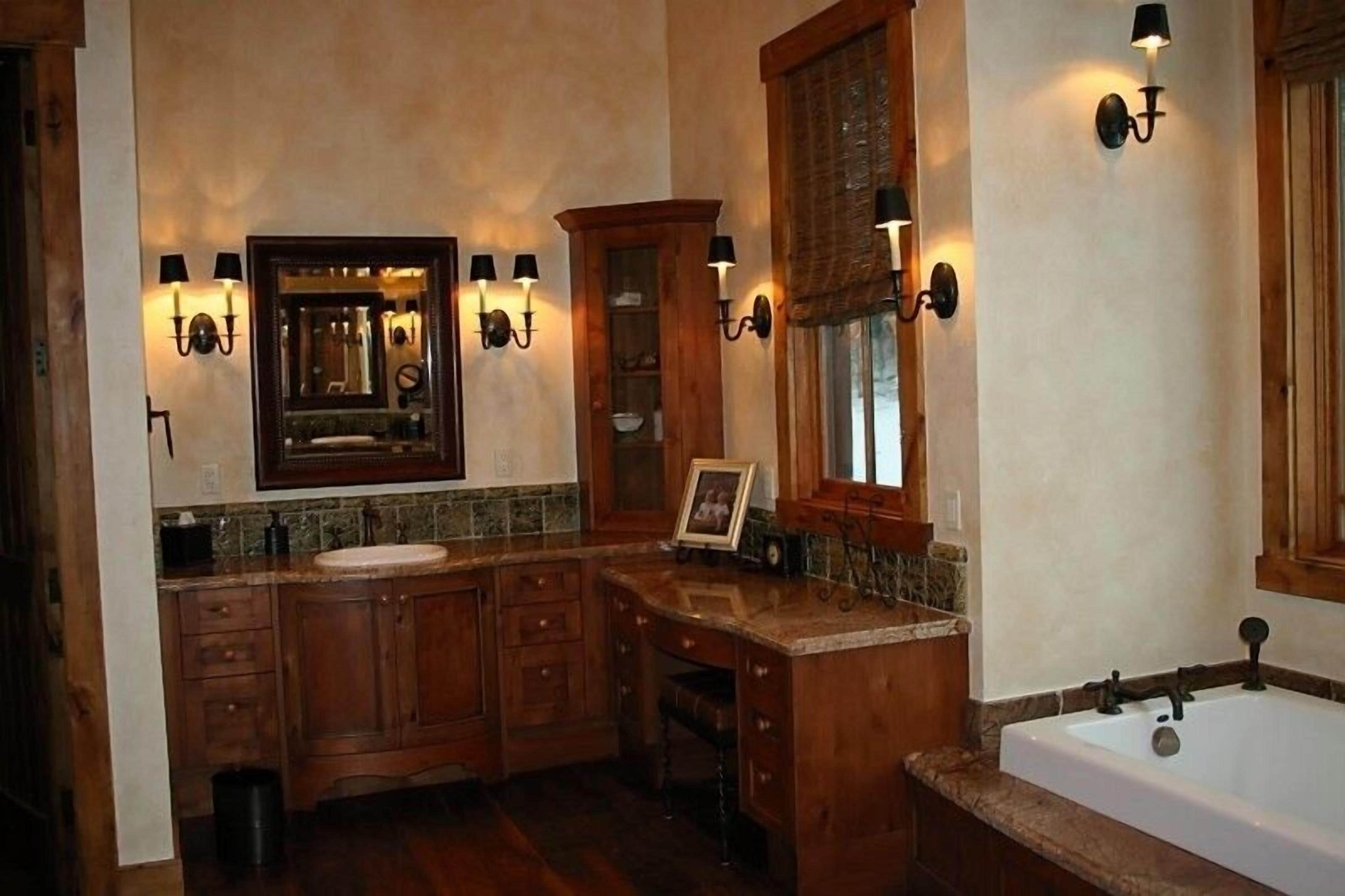 Une salle de bain spacieuse dotée d’un grand meuble-lavabo, d’une baignoire et d’un éclairage mural.