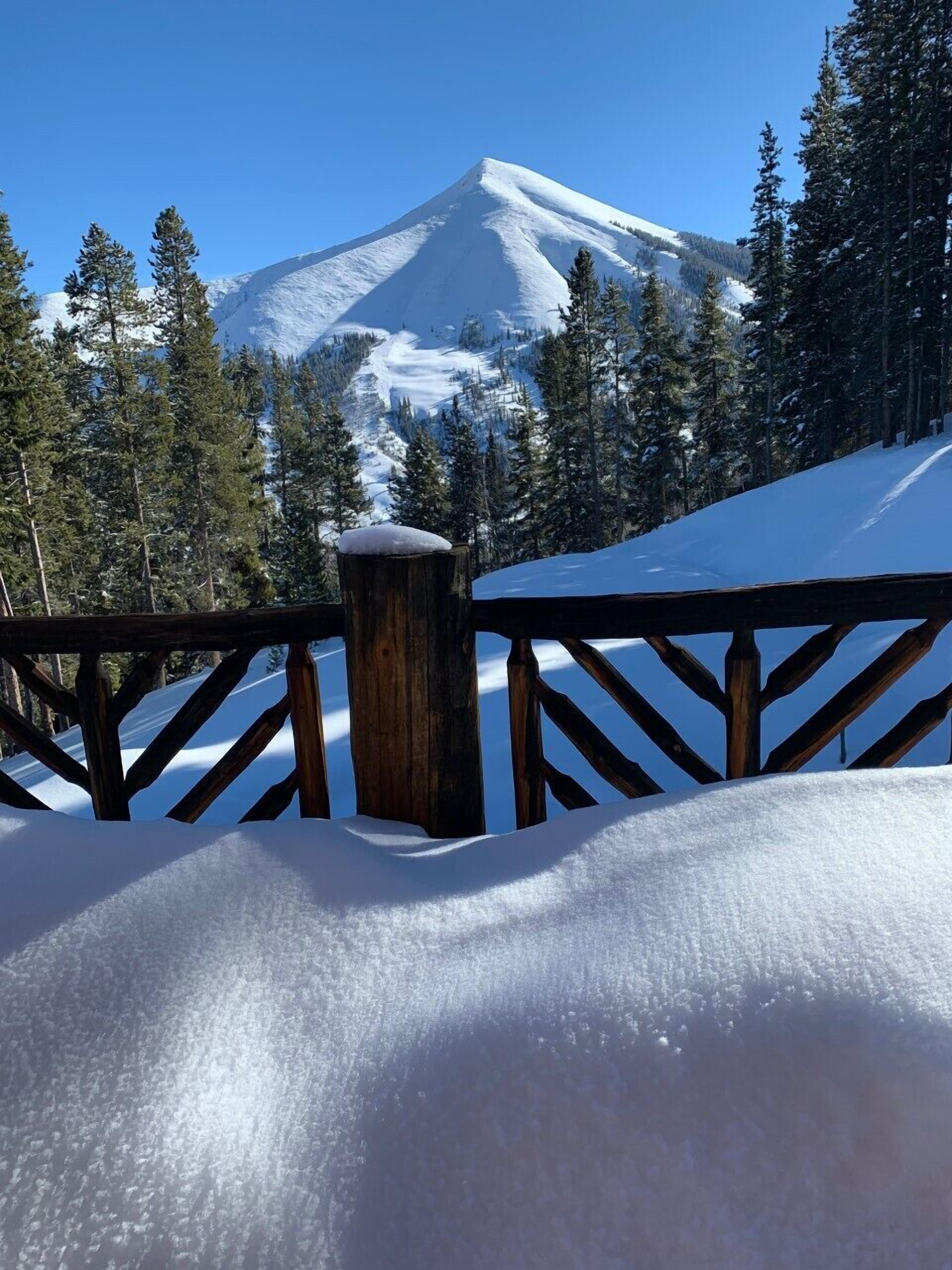 A snow-covered mountain with a wooden railing in the foreground.