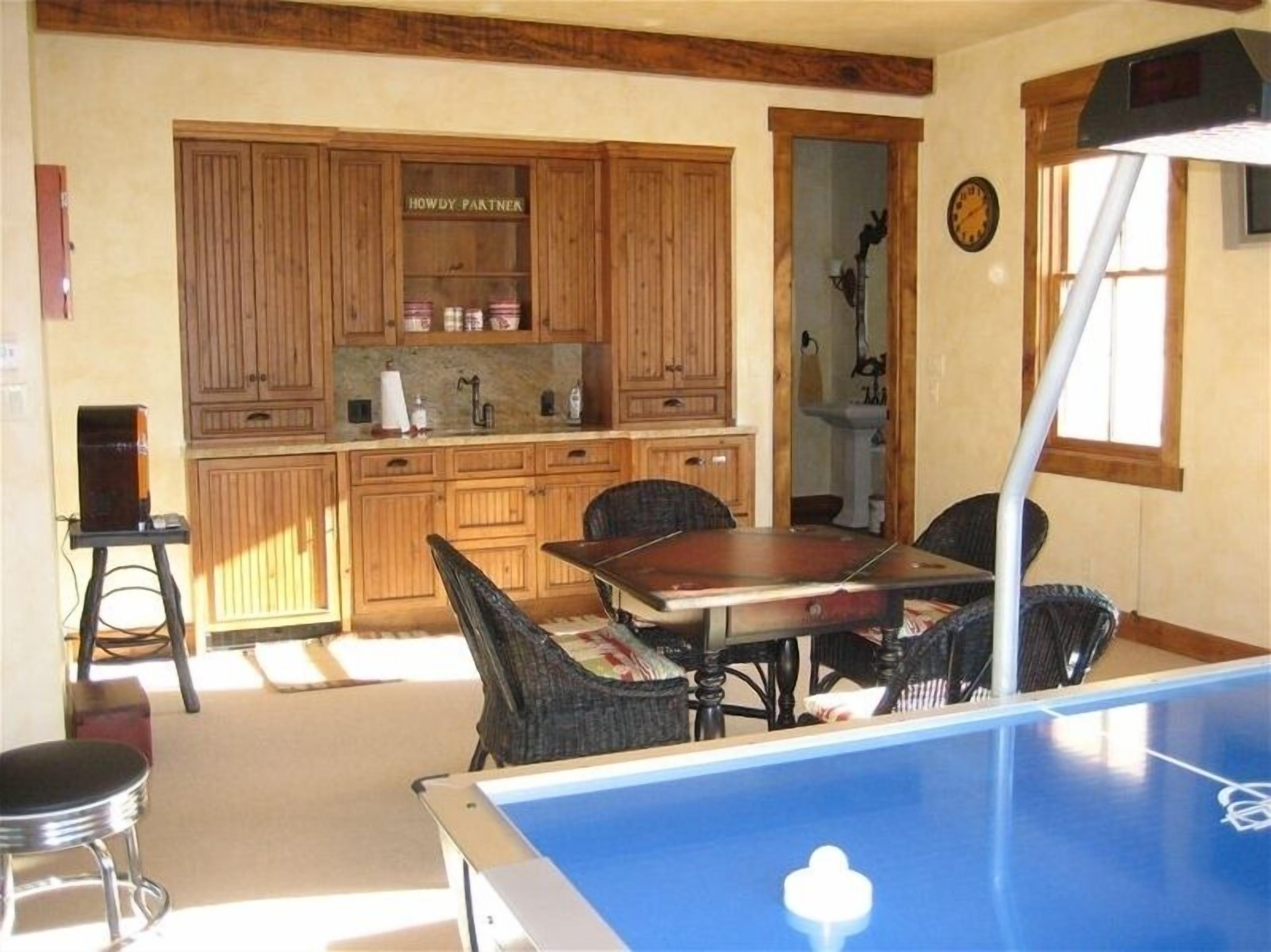 A room with a pool table, wooden cabinets, and a dining table with chairs.