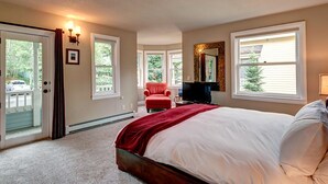 Ein Schlafzimmer mit einem großen Bett, einem roten Sessel, einem Fernseher und einem Spiegel an der Wand.