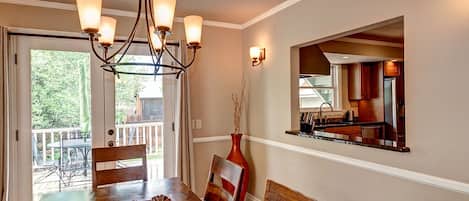 Enjoy meals in this dining area with a table for four, a chandelier, and a large window offering a view of the outdoors.
