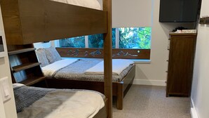Une chambre avec un lit superposé, une télévision et une fenêtre donnant sur les arbres.
