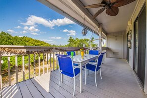 A covered outdoor area with a table and chairs, a ceiling fan, and a view of a green landscape. - 3 Bedroom Condo Sleeps 7 - One Block from Beach (Surfside Beach)