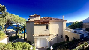 A Mediterranean-style building with a tiled roof, a small balcony, and a view of the sea.