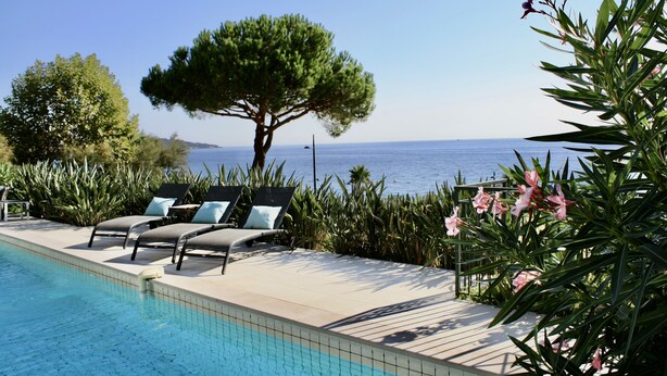 A poolside area with lounge chairs and a view of the sea. - Premium Beachfront Villa, Panoramic View of St Tropez Bay (Sainte-Maxime)