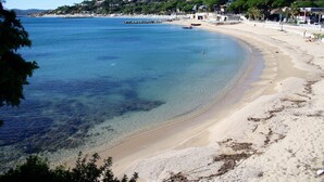 A beach with clear water, a sandy shore, and buildings in the background. - Premium Beachfront Villa, Panoramic View of St Tropez Bay (Sainte-Maxime)