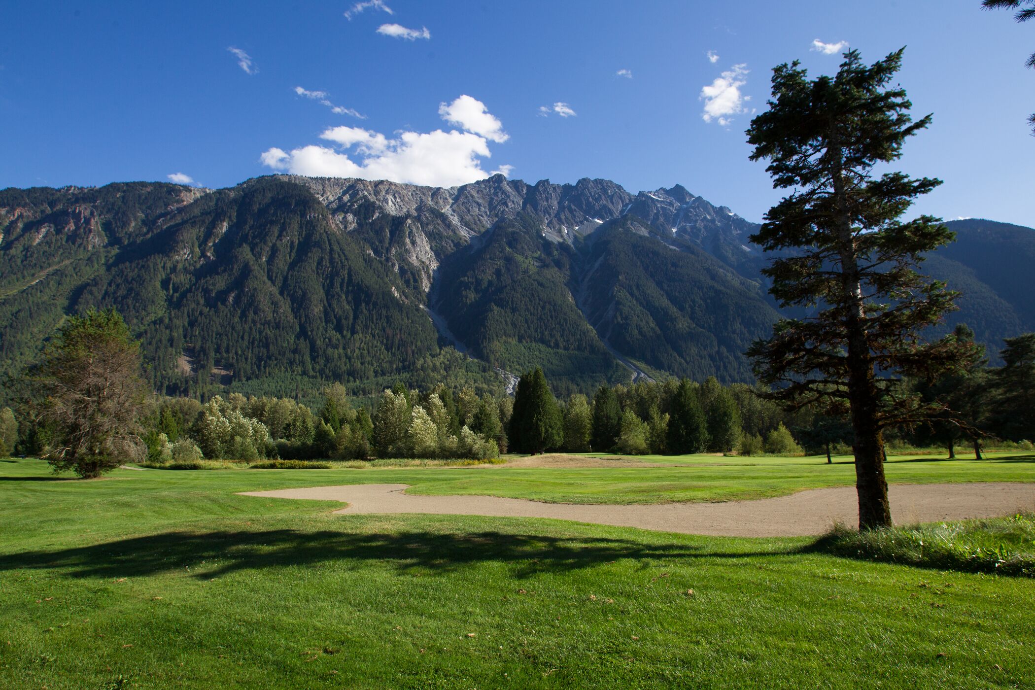 A golf course with a mountain backdrop.
