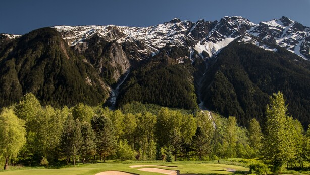 En golfbane med et bjerglandskab i baggrunden.