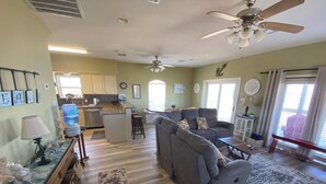 A spacious living room with a gray sectional sofa, a wooden coffee table, and a kitchen area with white cabinets and a built-in dishwasher. - Spacious 4 B/R 3 BA - best of both - Bay and Gulf  (Surfside)