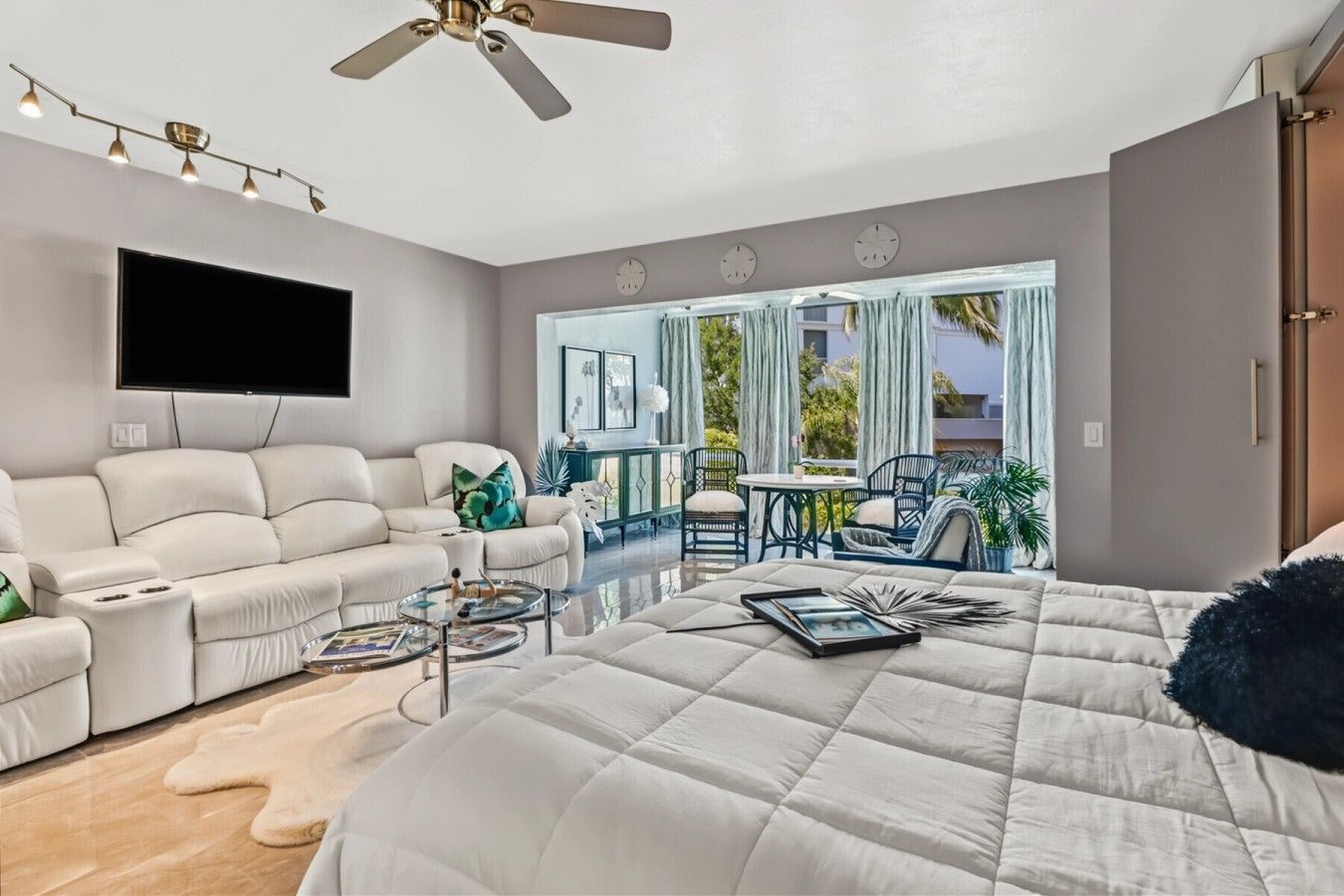 Ein modernes Schlafzimmer mit einem großen Bett, einer Couch, einem Couchtisch und einem Balkon mit Sitzgelegenheit.