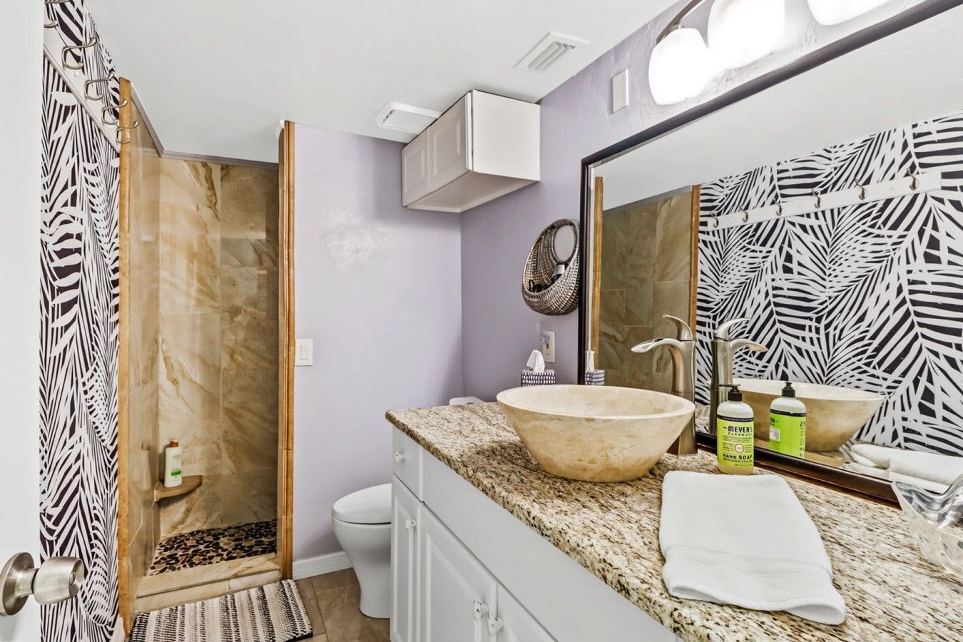 Une salle de bain avec un grand miroir, un lavabo et une douche.