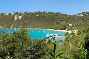 A coastal view with boats docked near a beach, surrounded by greenery and buildings on a hillside. - Idyllic Villa - Great Pool and deck areas, great family home, A/C throughout (Cruz Bay)