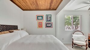 Una camera da letto con un letto grande, una sedia e quattro quadri appesi al muro.