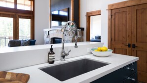 Una cocina moderna con un lavamanos grande, armarios de madera y un cuenco de limones en la encimera.
