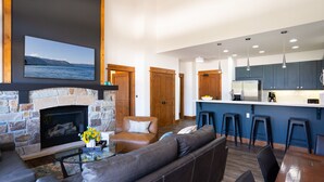 Una sala de estar moderna con chimenea de piedra, sofá de cuero y televisor montado en la pared.