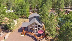 Eine Hütte mit einer Terrasse, einer Veranda und Blick auf die umliegenden Bäume.