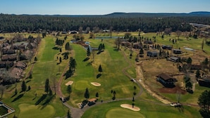 Luftaufnahme eines Golfplatzes mit mehreren Bunkeranlagen, einem Wasserschutzgebiet und Wohnhäusern, die die Spielbahn umgeben.