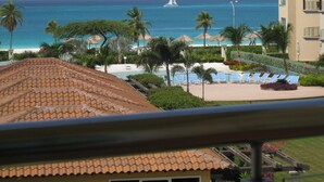 Een resort met een zwembad, palmbomen en uitzicht op de oceaan.