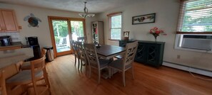 A kitchen with a dining table, chairs, a coffee maker, and a cabinet.