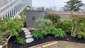 A garden with stepping stones, a wooden fence, and a shed.