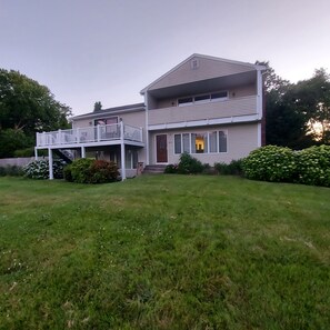 A two-story house with a front porch, a covered deck, and a well-maintained lawn. - Newly Refreshed! Prime Location - Walk to Nrgst Pier Beach or Narrow River. (Narragansett)