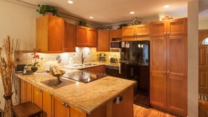 A kitchen with wooden cabinets, granite countertops, a stainless steel refrigerator, and a built-in oven. - Spacious 1 Bedrm Unit. Stunning Ocean View, in South Kihei, Maui.  (Kihei)