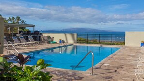 A swimming pool with lounge chairs and a view of the ocean. - Spacious 1 Bedrm Unit. Stunning Ocean View, in South Kihei, Maui.  (Kihei)
