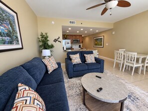 A living room with a sofa, a round coffee table, and a ceiling fan.