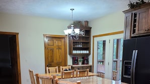 A kitchen with a wooden dining table, chairs, a built-in oven, and a refrigerator.