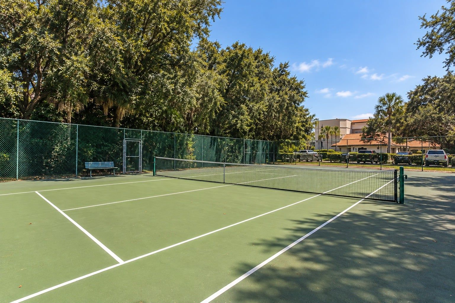 Una cancha de tenis con una red, rodeada de árboles y una valla.