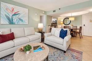 A living room with two sofas, a coffee table, and a dining area with a table and chairs.