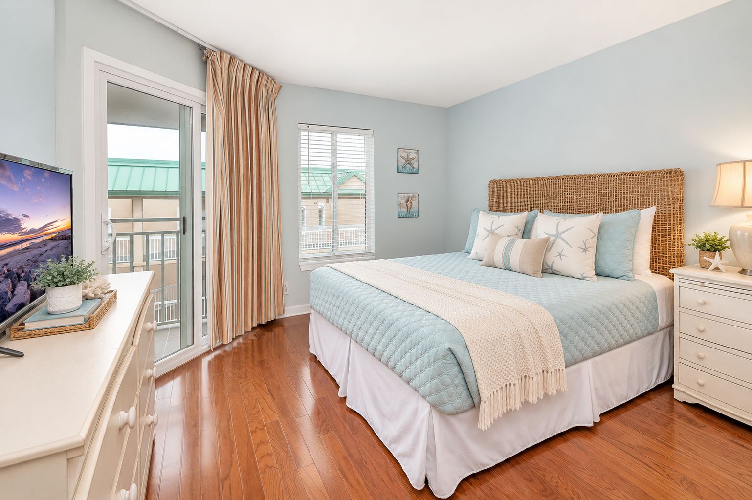 A bedroom with a bed, a dresser, a television, and a window with curtains.