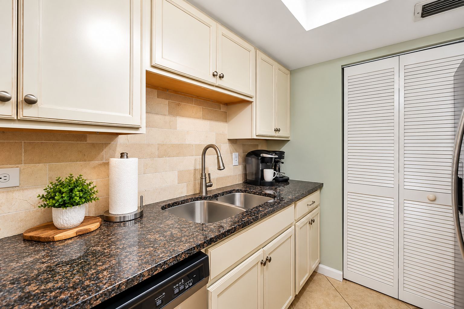 A kitchen with a granite countertop, stainless steel sink, and a coffee maker.