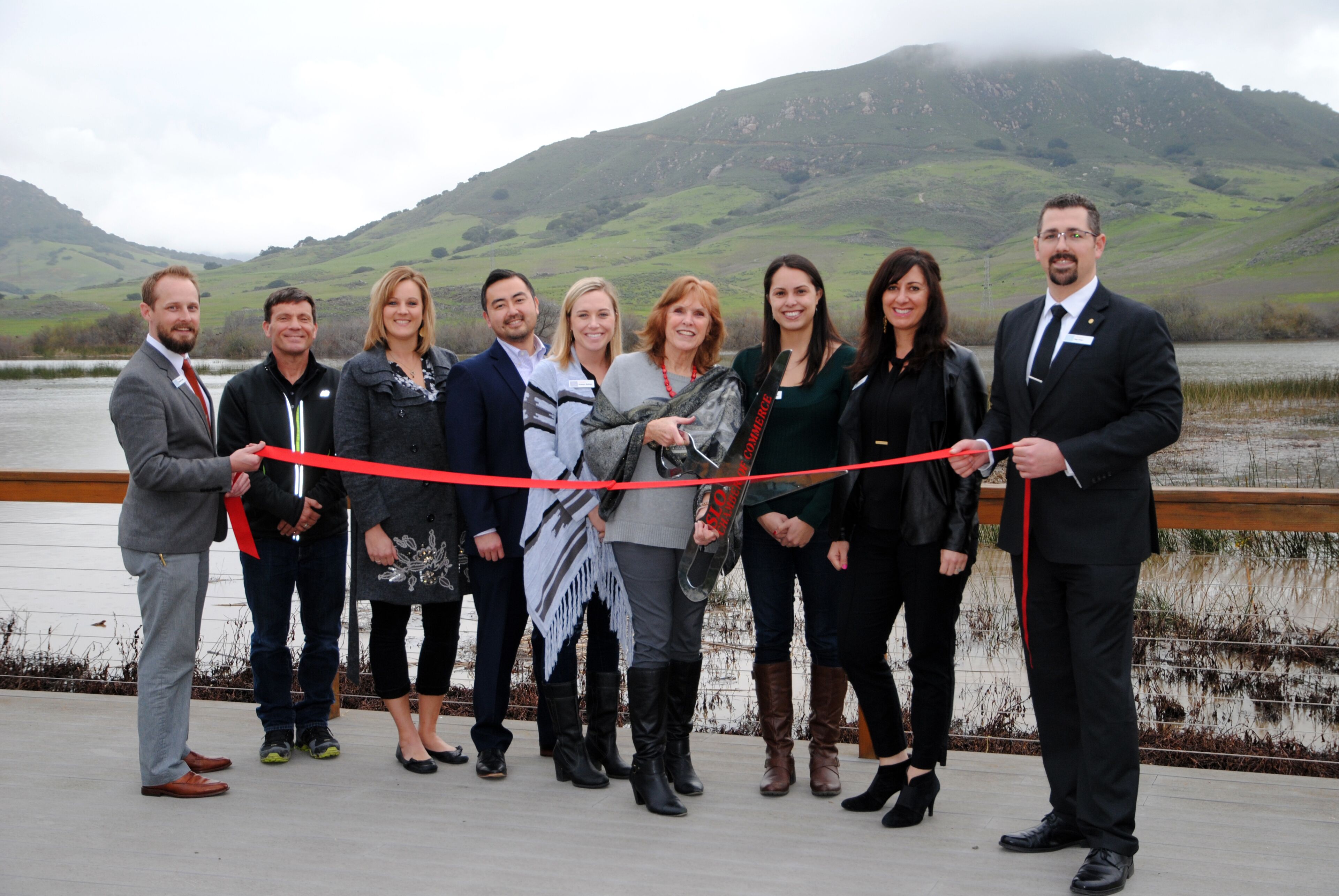 A group of people standing on a bridge with a scenic mountainous background.