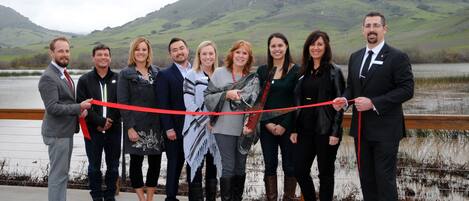 A group of people standing on a bridge with a scenic mountainous background.