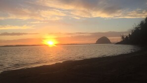 Un atardecer sobre un cuerpo de agua tranquilo, con la silueta de una colina a lo lejos.