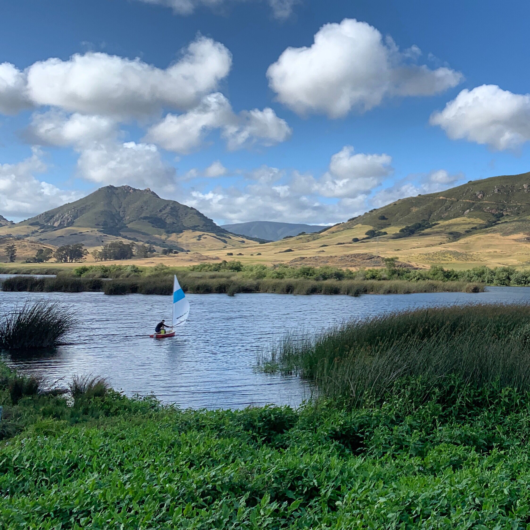 A person sailing on a calm lake with mountains in the background.