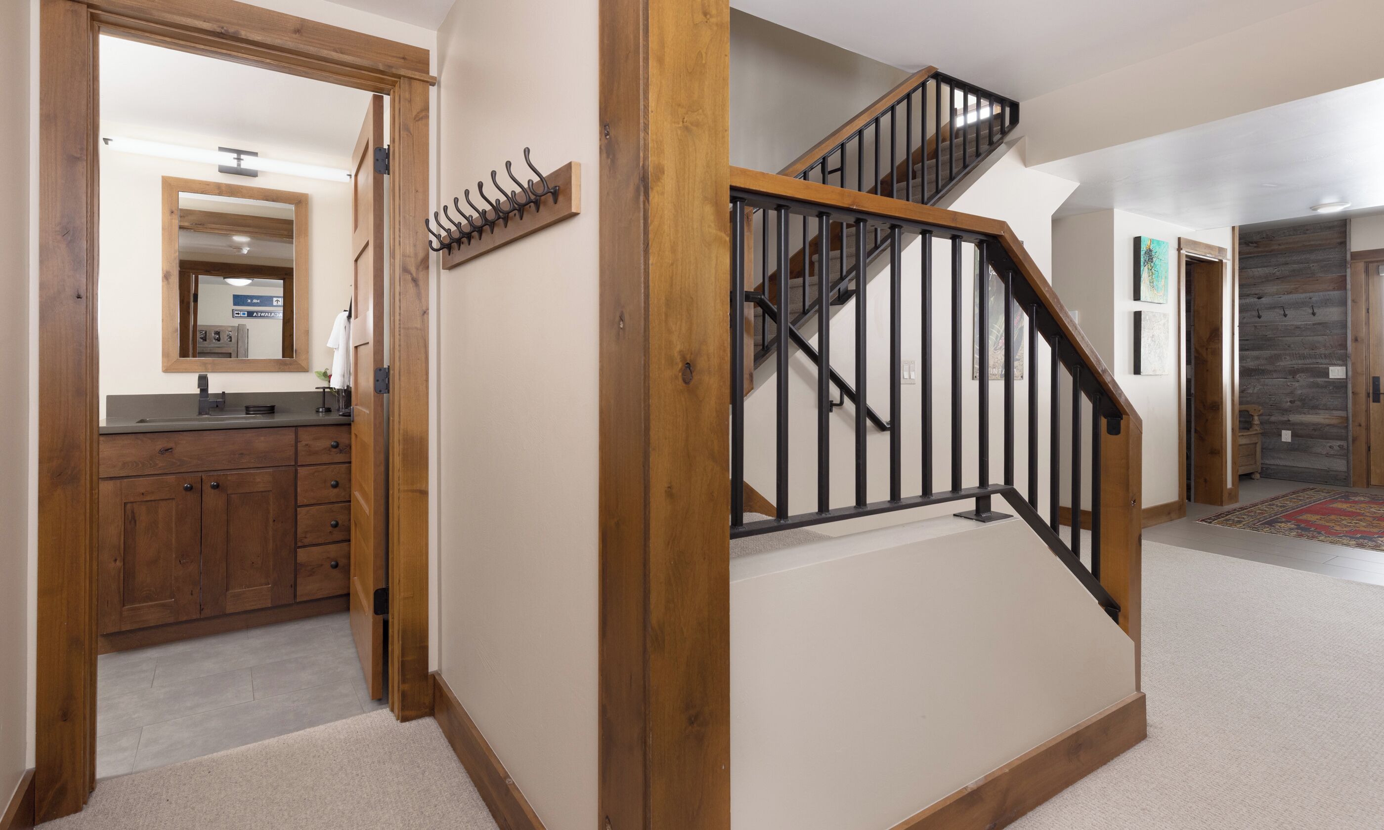 A staircase with wooden handrails and black metal balusters, leading to an upper floor.
