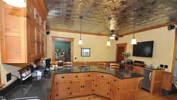 A kitchen with wooden cabinets, a granite countertop, a built-in island, and a ceiling with a textured design.