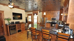 A spacious kitchen with wooden cabinets, a large island with bar stools, stainless steel appliances, and a ceiling fan.