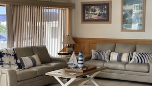 Ein Wohnzimmer mit zwei Sofas, einem Couchtisch und einem Bild an der Wand.
