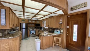 Eine Küche mit Holzschränken, einem Edelstahlkühlschrank, einer Mikrowelle und einem Herd.