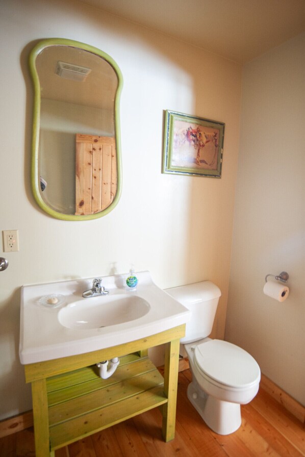 A bathroom with a white sink, green vanity, and a white toilet.