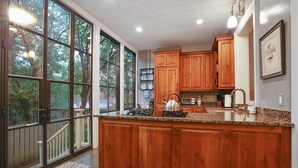 A kitchen with wooden cabinets, a granite countertop, and a large window.