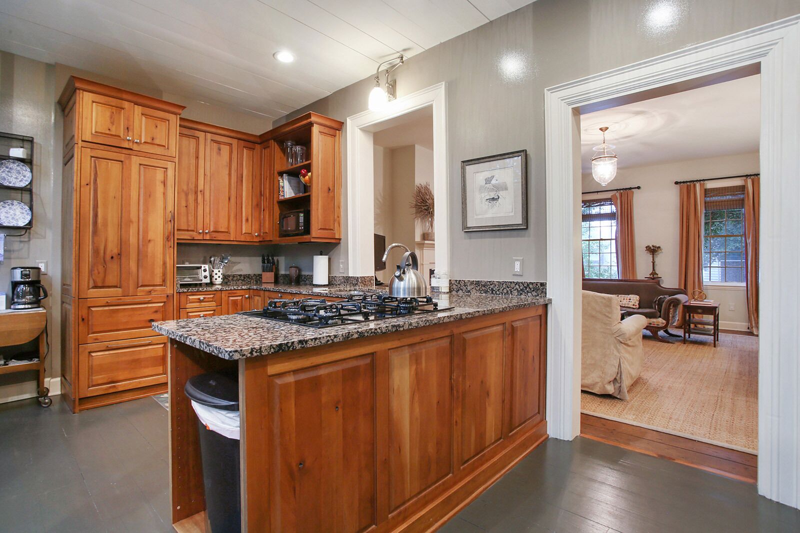 A spacious kitchen with wooden cabinets, a granite countertop, and a central island with a stove.