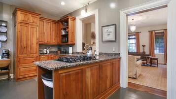 A spacious kitchen with wooden cabinets, a granite countertop, and a central island with a stove.