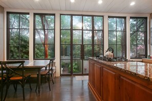 Una cocina con ventanas amplias, un comedor con sillas y una encimera de madera.