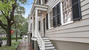 A two-story house with a brick pathway leading to a white staircase.