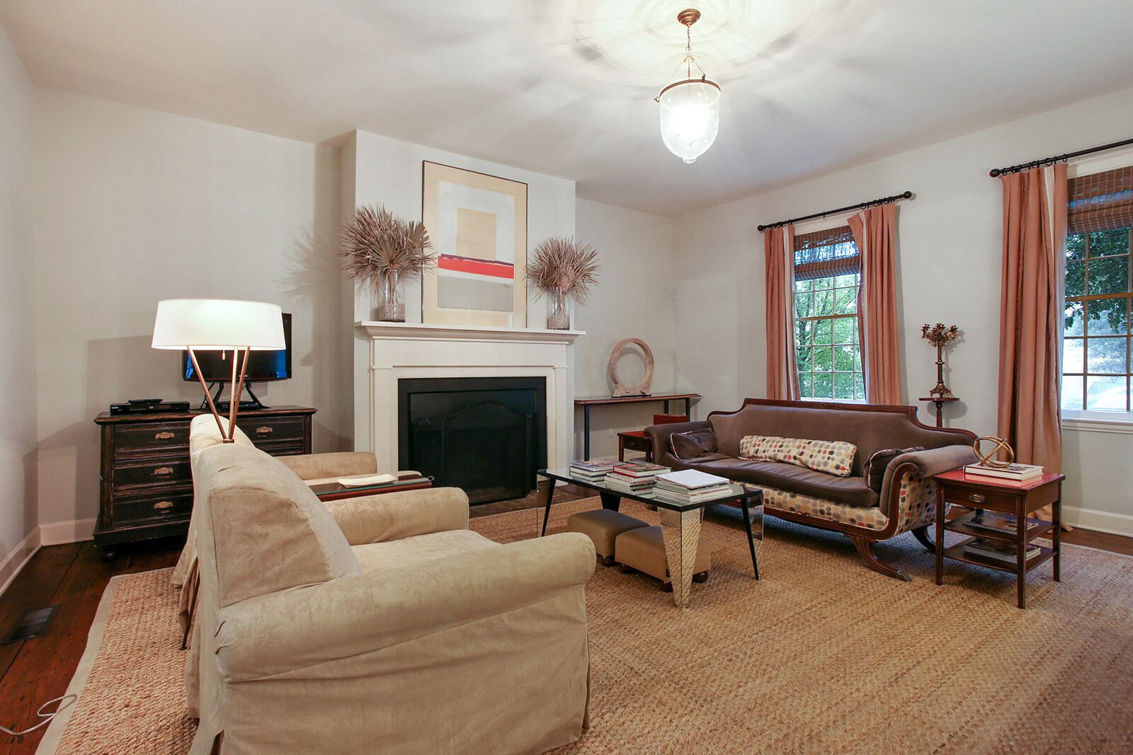 A living room with a fireplace, sofa, armchairs, a coffee table, and a television.